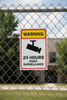 Video surveillance warning sign on a chain-link fence with a building in the background.