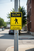 Slow pedestrian crossing sign installed on a pole at an intersection