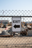 EXIT sign with an arrow pointing right on a chain-link fence at a construction site.