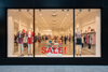Storefront with mannequins wearing clothing and a 'SALE!' sign.