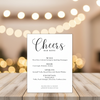 Bar menu with 'Cheers' title on a wooden table with blurred lights in the background